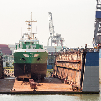 A large vessel rests in a drydock, awaiting repairs