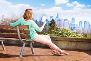 A woman sits on a park bench, reading a book with the Seattle skyline in the background