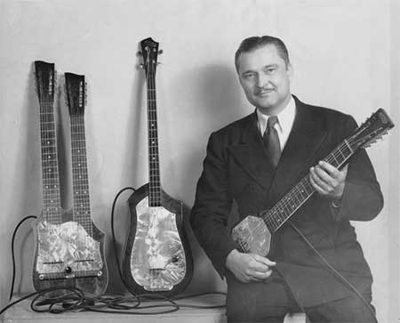 Seattle native Paul Tutmarc, poses with his invention, the Audiovox 736 Electric Bass guitar.