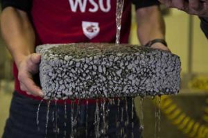 A researcher at Washington State University holds a sample of permeable, carbon fiber infused concrete that lets water drain naturally.