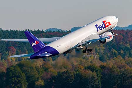 A Fed Ex freighter takes off from an airport.