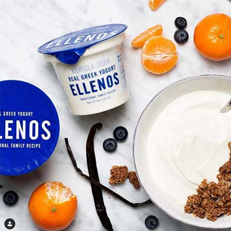 Ellenos Yogurt on a table with fruit and spices.