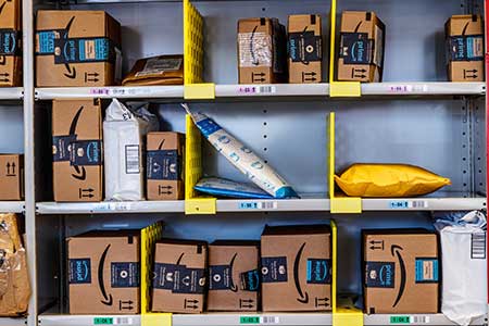 A bunch of Amazon boxes await delivery in a warehouse.