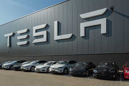 Tesla electric cars parked outside of a Tesla plant.