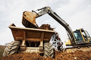 A large digger loads dirt into a waiting dump truck