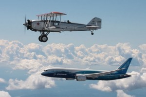 Two planes fly in formation, one a biplane, the other a modern jet