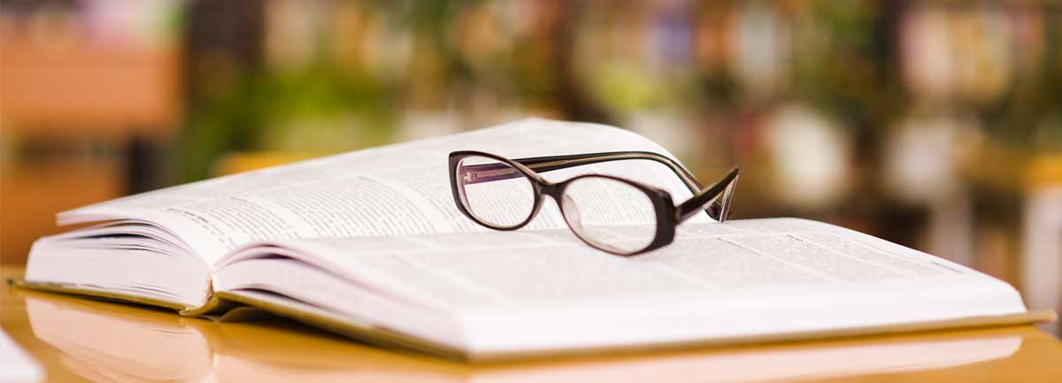 A pair of glasses rest on a book in a library