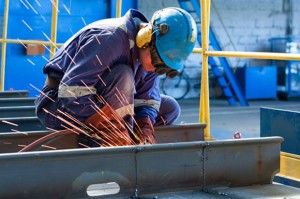 A worker welds two plates together in a drydock