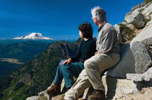 A couple enjoys their view of Mount Rainier from a rock outcropping