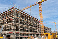 A crane lifts some construction materials onto a building under construction