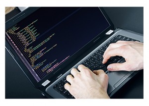 A programmer reviews computer code on a laptop