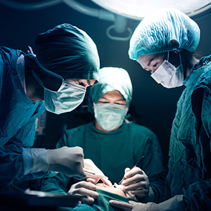 A doctor and two nurses perform an operation in a surgical suite