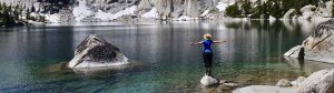 A hiker enjoys a crystal clear lake in the Cascade Mountains.