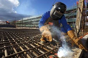 A welder reinforces rebar before concrete is poured onto a new foundation.